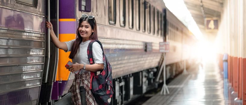 Portrait attraction asian woman boarding a train at train station for travel in summer. Travel concept