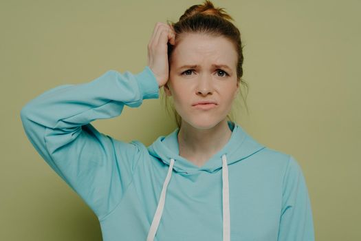 Young confused brunette woman in blue hoodie
