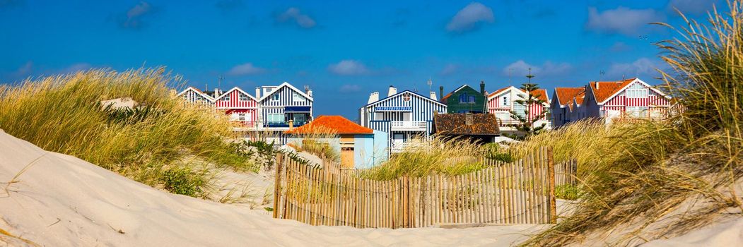 Idyllic and quaint beach houses seen from beach dunes. Beach houses with colorful stripes from Costa Nova, Aveiro, Portugal.