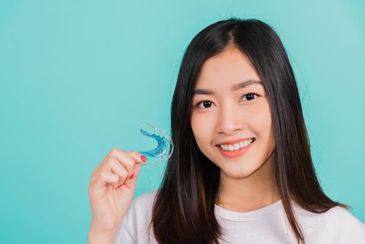 woman smiling holding silicone orthodontic retainers for teeth
