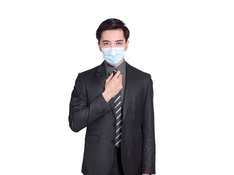 young businessman wearing  medical mask during the COVID-19 pandemic, confidently adjusts his tie in front of the camera