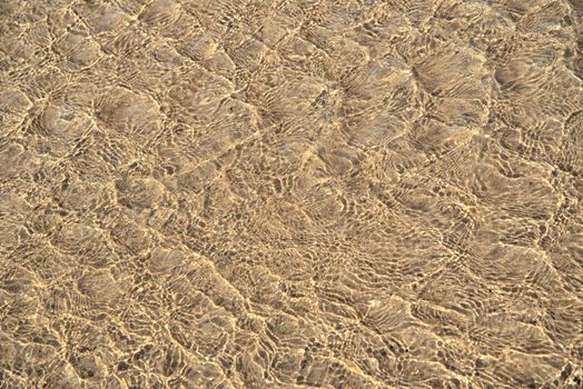 Surface of sea water with ripples on beach sand.