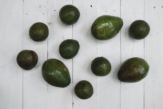 Whole and halved avocado on wooden table 