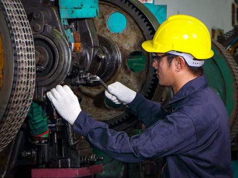 Asian technician Wear a uniform, helmet, use a wrench to inspect machines,