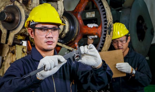 Asian engineer Safety uniforms use vernier calipers to measure workpieces.