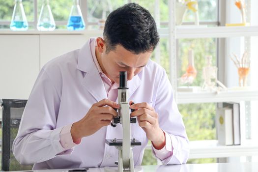 Asian scientists or chemists use a microscope.