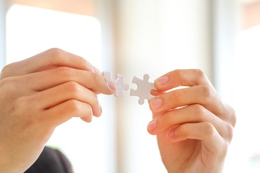 A close up of a businessman holding a piece of the puzzle