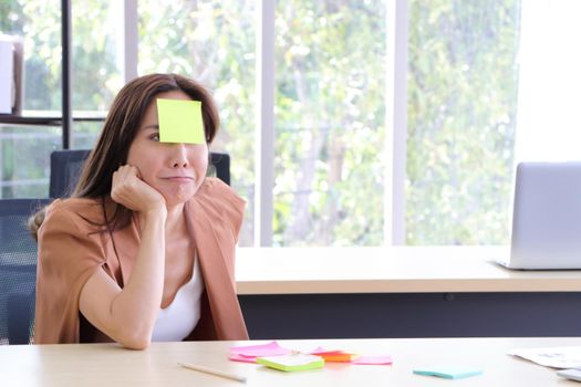 Asian businesswomen look and write a post-it note on their faces to relax and smile from work