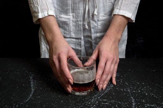 Woman hand holdin a glass with dark beer