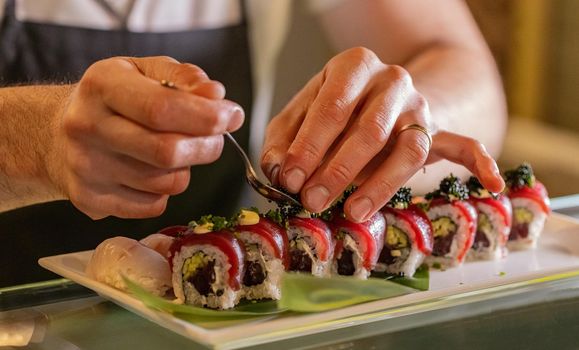 Chef’s hands decorating traditional japanese sushi 