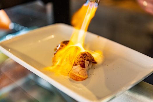 Chef using kitchen torch burn on salmon sushi