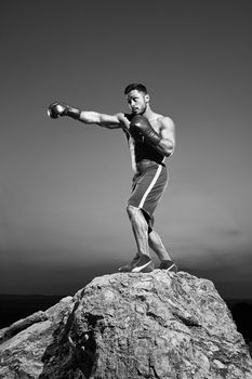 Monochrome shots of a fierce male boxer training outdoors