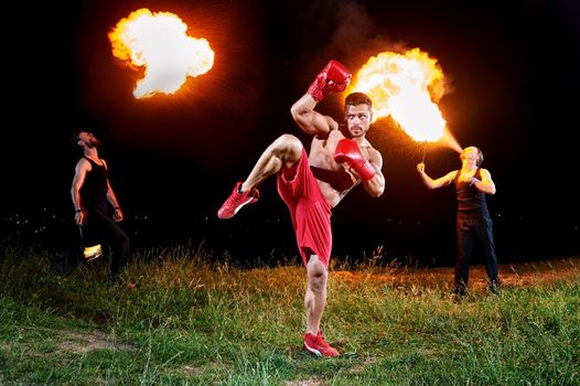 Ripped male boxer posing outdoors at night fire show performance