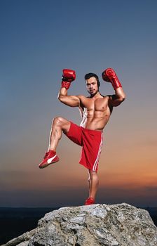 Muscular male boxer training outdoors