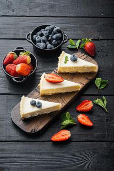 Portion of cheesecake with berries, on black wooden table background
