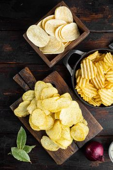 Variation different potato chips, on old dark wooden table , top view flat lay