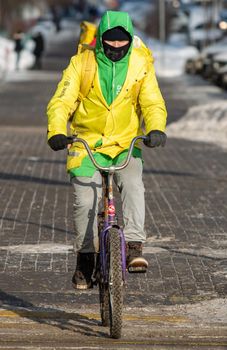 February 7, 2021. Moscow, Russia. A courier of the Yandex Food delivery service on a bicycle ride on a Moscow street on a frosty winter day.