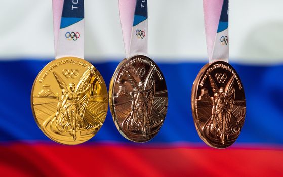 April 25, 2021 Tokyo, Japan. Gold, silver and bronze medals of the XXXII Summer Olympic Games 2020 in Tokyo on the background of the flag of Russia.