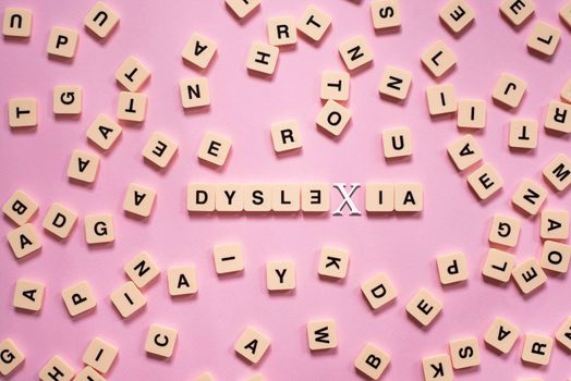 Alphabet tile blocks with DYSLEXIA word in the center on pink background