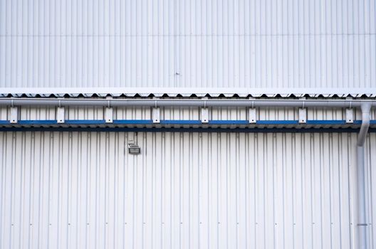 White corrugated iron sheet used as a facade of a warehouse or factory. Texture of a seamless corrugated zinc sheet metal aluminum facade. Architecture. Metal texture.