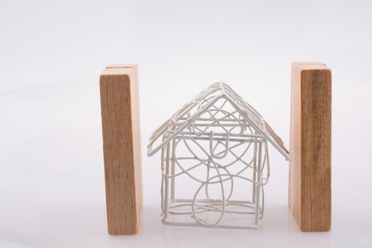 Little wired metal model house  between two domino pieces