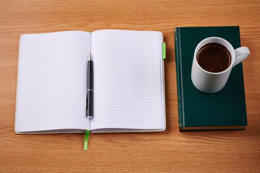Plain Blank Notebooks And A Pen Beside A Cup Of Coffee Placed Book Table. Simple Empty Notepads With A Ballpen And Mug Over Dictionary Desk.