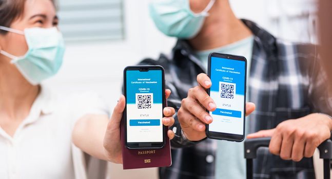 couple woman and man ready to travel showing digital vaccine health passport certificate app in smartphone
