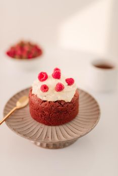 Raspberry muffin with cream on stand over white background