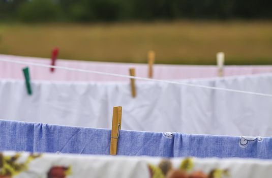Washed colorful cotton bed sheets hanging on a clothesline outdoors