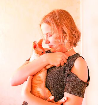 Happy young teenager girl holding adorable little devon rex cat