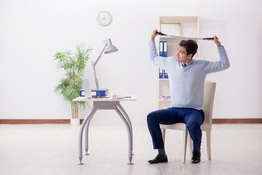 Man exercising with elastic band in office during lunch break