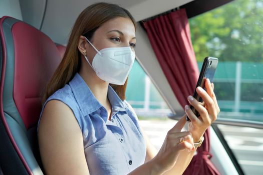 Relaxed young woman with KN95 FFP2 face mask using smart phone on public transport