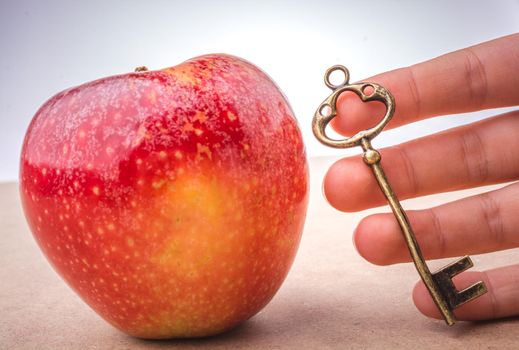 Hand holding a key beside an apple