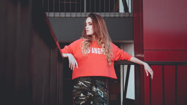 Fashion model wearing red hoodie with inscription los angeles posing at parking