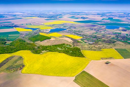 Aerial rural landscape in Romania, canola fields, forest, villages and lakes