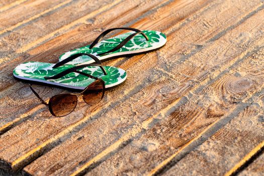 Green flip flops and sunglasses on the wooden boards