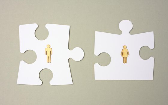 white puzzles and wooden men on a gray background. Recruitment concept, team compatibility, individuality.